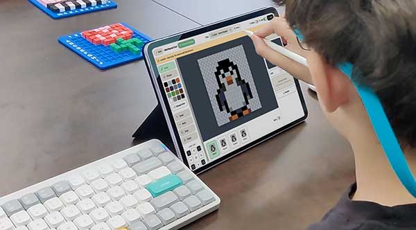 A young creator drawing a pixel-art penguin in Pixel Game Lab